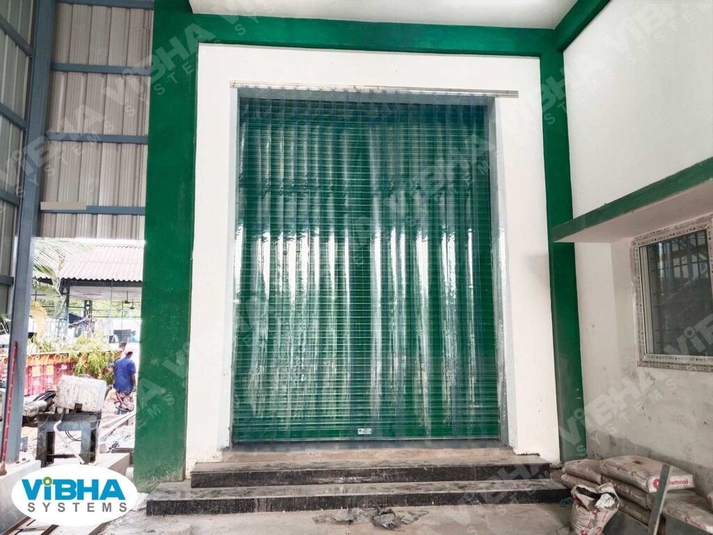 Heavy-duty PVC strip curtains covering factory shutter opening to block dust and noise.