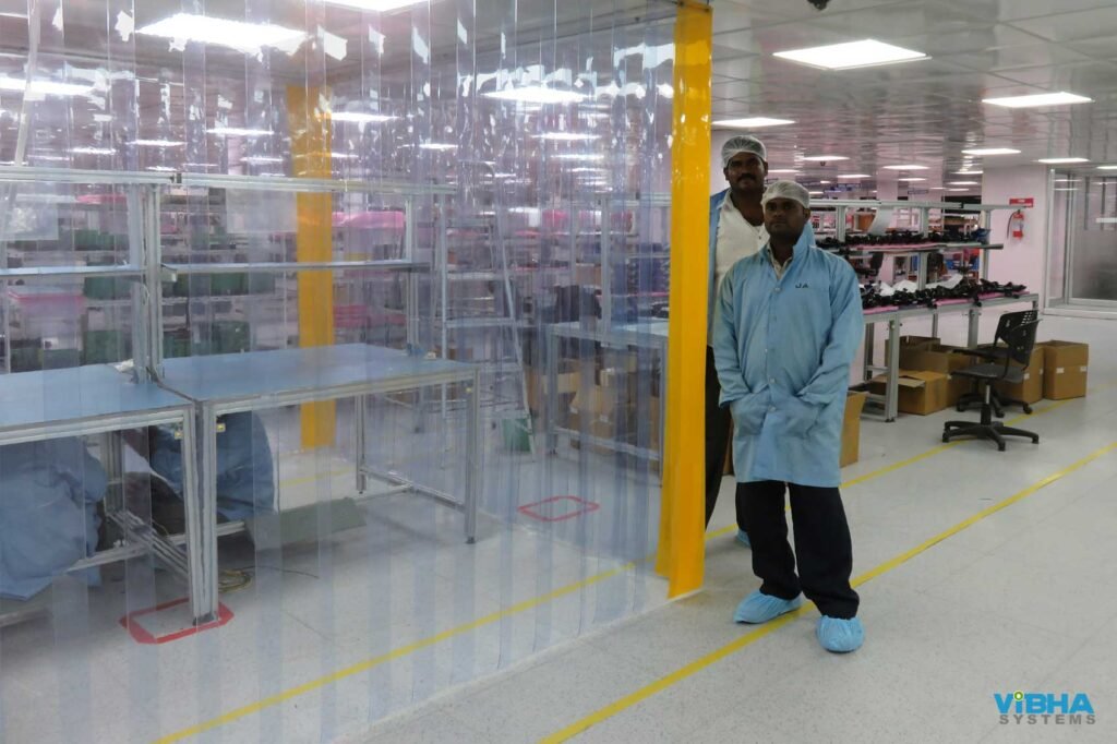 Clear PVC strip curtains enclosing industrial machinery inside a workshop.